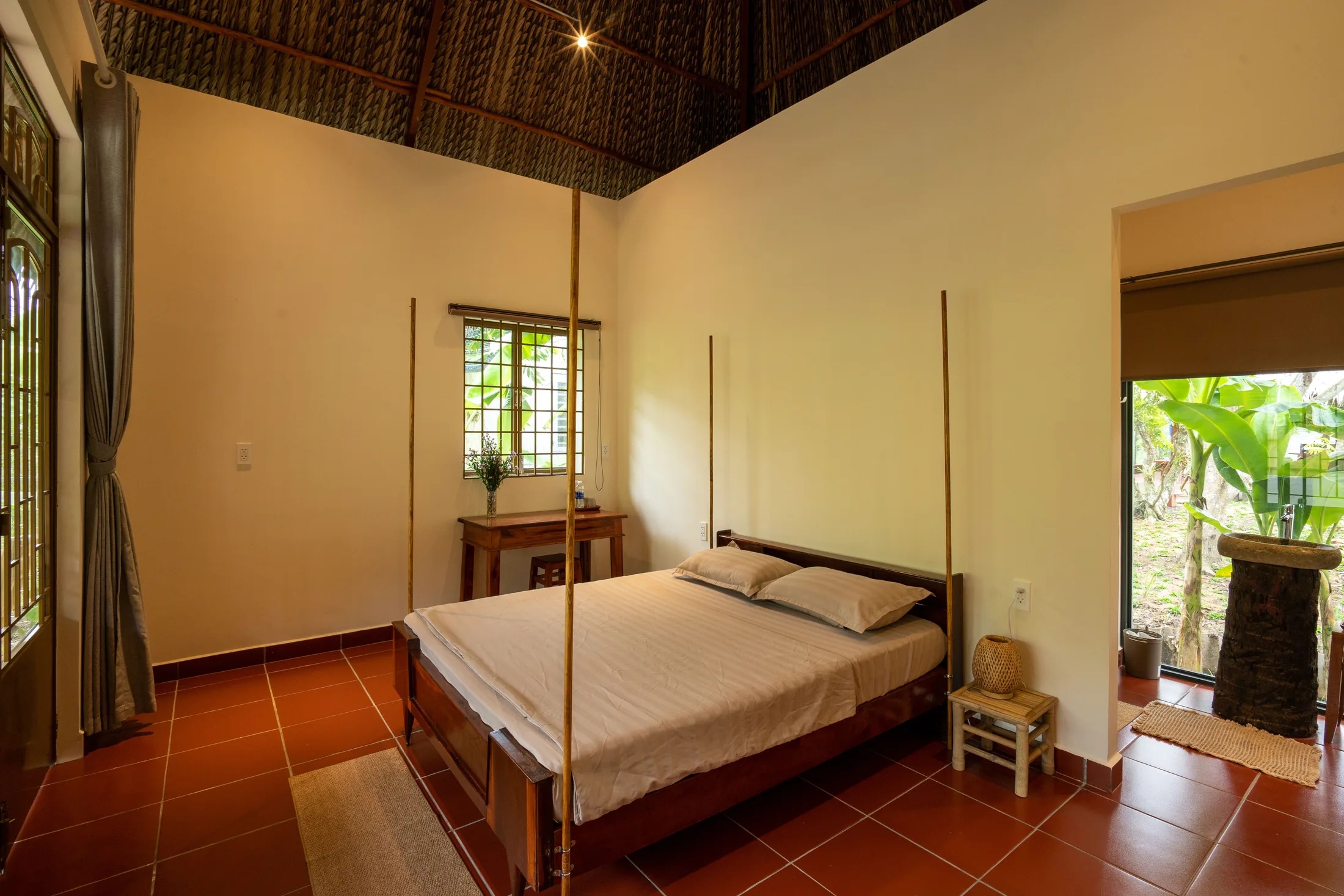 Wooden bed and high thatched roof in Coconut Bliss bungalow