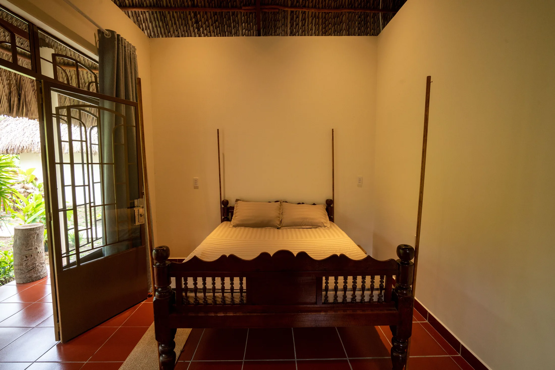 Wooden bed and garden-facing doors inside Mango Suite